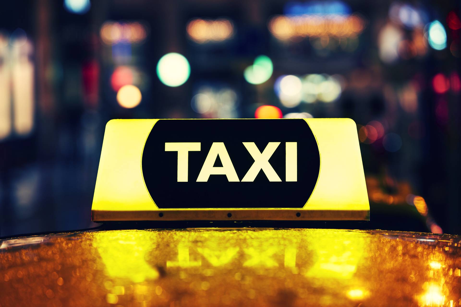 Illuminated taxi sign on top of cab at night